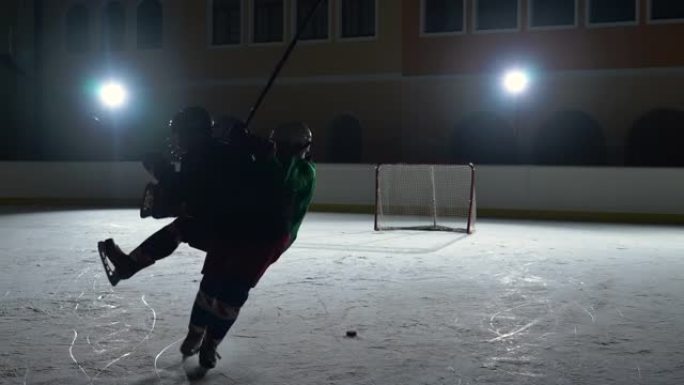 两名身穿制服，戴着曲棍球棒的头盔的男子在冰场上滑冰并相互碰撞。职业曲棍球运动员在带有聚光灯的黑暗溜冰