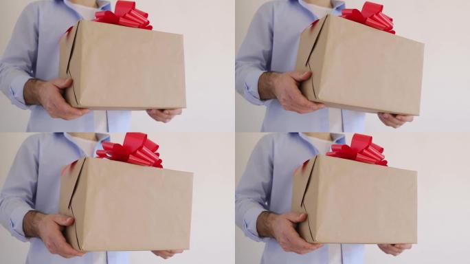 男人的手拿着一个带有红色蝴蝶结的礼品盒。快递，圣诞节大甩卖。网上购物。情人节