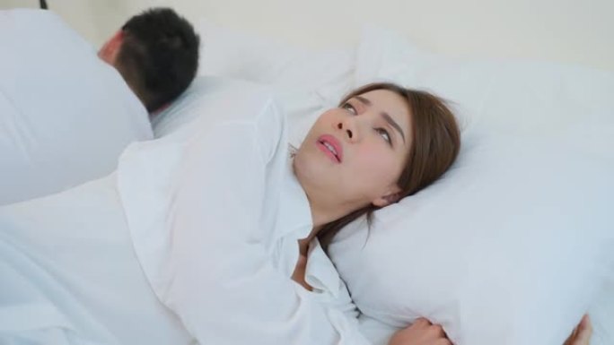 亚洲年轻夫妇躺在床上，吵架后痛苦不堪。新婚男女为争吵冲突和在卧室睡觉感到心碎。家庭问题 -- 分离概
