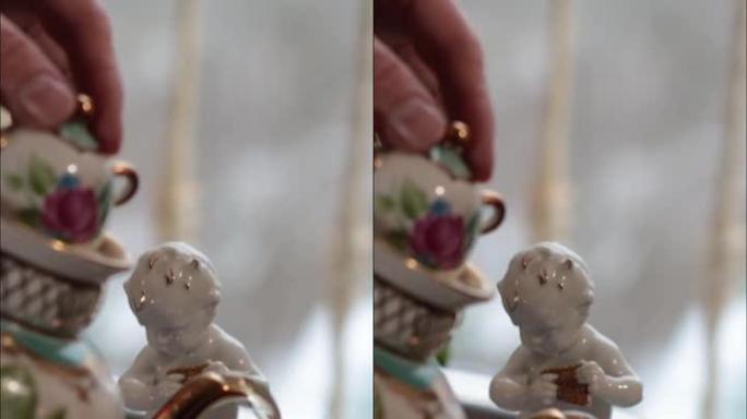 白瓷天使小雕像和手倒茶从华丽的茶壶到茶杯