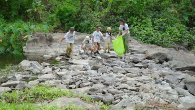 亚洲志愿者和儿童正在收集塑料瓶，这些塑料瓶流经溪流进入垃圾袋，以减少全球变暖和环境污染。志愿服务和回