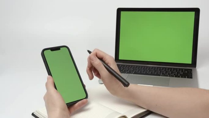 使用绿屏电话的女人。智能手机和笔记本电脑上的绿屏模拟