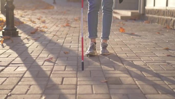 近景一名女子拄着拐杖为视障人士助威，是在夕阳西下的城市里慢动作
