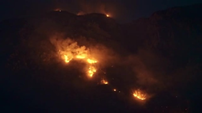 山中野火的高ISO鸟瞰图。落基山脉中燃烧的树木和草地的夜景。黑山的季节性火灾。气候变化与全球变暖