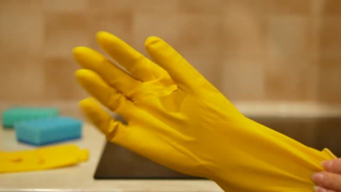 女人的手将黄色清洁手套放在舒适厨房的电磁炉前-4K，特写，黄色和蓝色