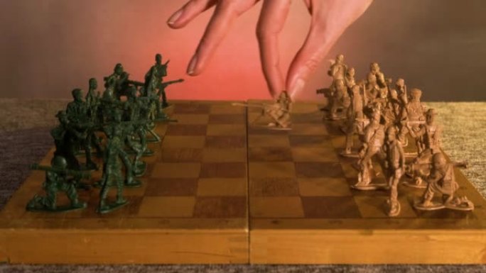 一个人的手在国际象棋中的一个塑料玩具士兵在棋盘上迈出第一步的特写镜头。一个大的政治游戏的概念