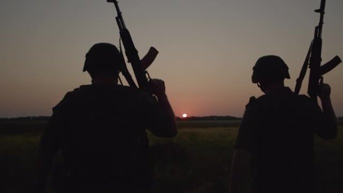 两名身穿特殊装备的军人手持步枪穿过田野。