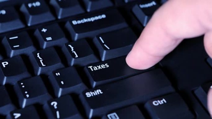 一只男性手按下电脑键盘上的税收按钮的特写