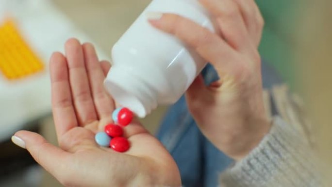 彩色药丸从药瓶中落在女人的手掌上。特写。药学和治疗概念，特写视图。