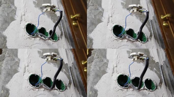 电开关挂在混凝土墙上的插座盒上的电线上。电的危险