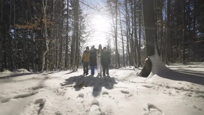 阳光明媚的日子，幸福的家庭在美丽的冬季森林徒步旅行