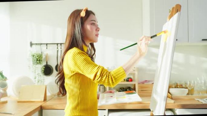 亚洲年轻才女艺术家在房子的画板上着色。迷人的美丽女性画艺术画，用水彩画和画笔创作艺术品在家享受创意活
