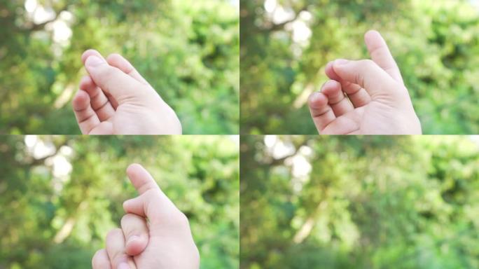 在绿色自然bokeh背景下弹指，积极的手势，手指弹指