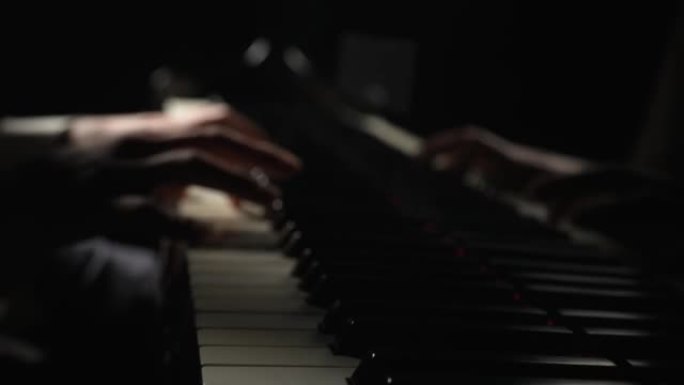 才华横溢的钢琴家在黑暗中用钢琴演奏古典旋律。人的手模糊的镜头触摸弦乐器的键。音乐艺术家的表演。特写。