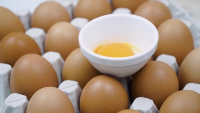 纸箱蛋盒中许多棕色鸡蛋之间的破碎鸡蛋旋转
