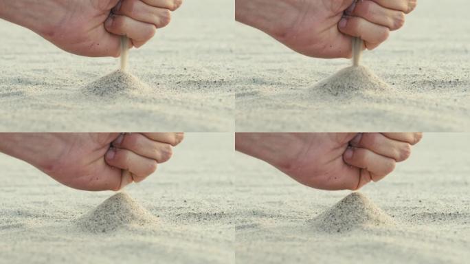 一个男孩的手从海滩上掉了一堆沙子