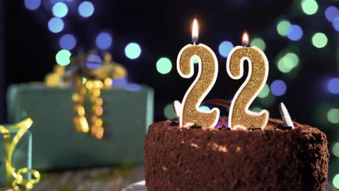 生日蜡烛22号放在桌子上的甜蛋糕上，距出生已有22年了。打火机上的火，吹灭节日蜡烛。