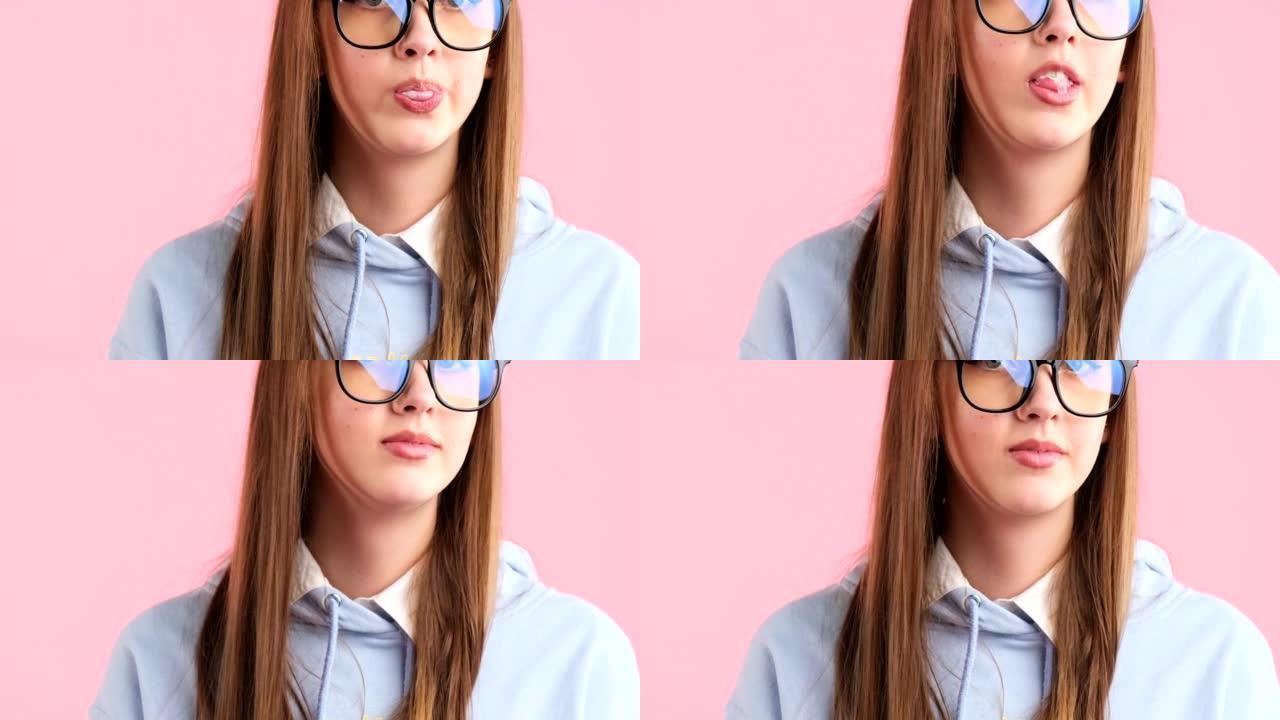 剪辑视频，一个漂亮的年轻金发少年戴着眼镜，在粉红色背景下摆出口香糖泡泡。