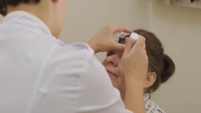 女性验光师在眼科诊所对患者的眼睛进行滴眼液