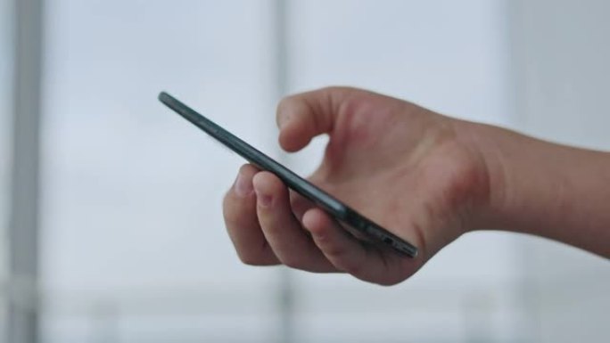 一个年轻人的手拿着黑色现代智能手机，点击触摸屏进行交流
