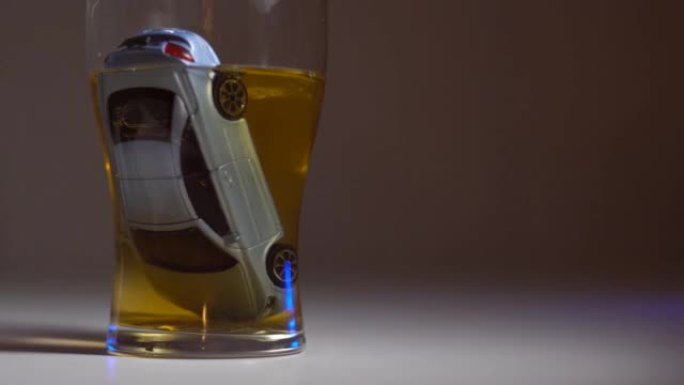 汽车淹没在一杯酒精中。社交广告。酒驾、车祸的概念。背景上闪烁的警灯。