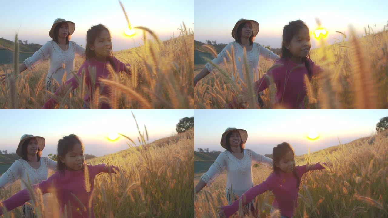日落时分的亚洲女孩和母亲走过草地