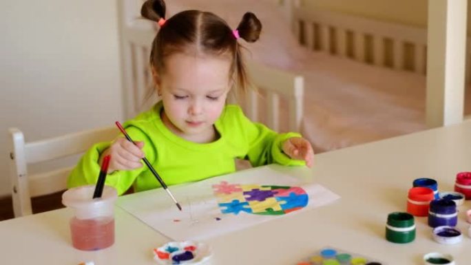 一个两岁的孩子用水彩颜料从不同的拼图中画出一颗五彩的心。
