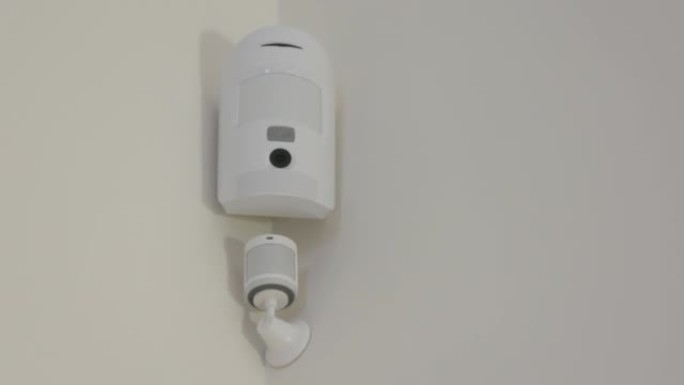 智能家居无线运动传感器用于报警系统和智能家居自动化，小型塑料白色运动检测器安装在客厅。