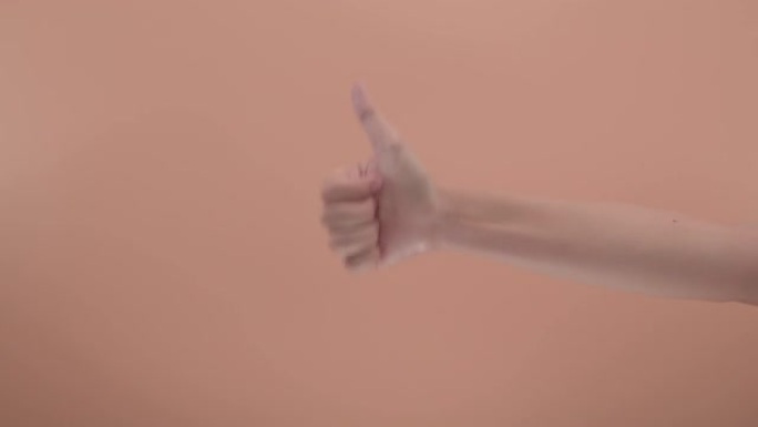 在工作室里，用彩色背景关闭女人的右手做手势意味着很棒。用肢体语言来传达意义。