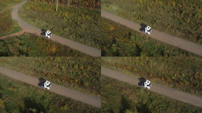 一辆没有拖车的半卡车独自在茂密的平坦森林沥青直线空旷的道路上行驶，高速公路自上而下的视图跟随车辆航拍