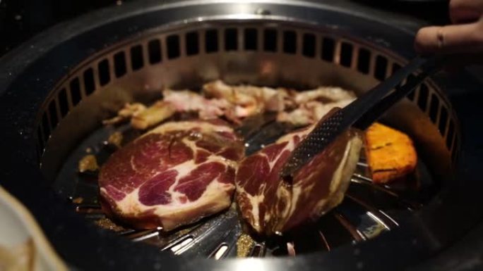 在传统的韩国餐厅，用手握钳在韩国烧烤盘上倒切猪肉。