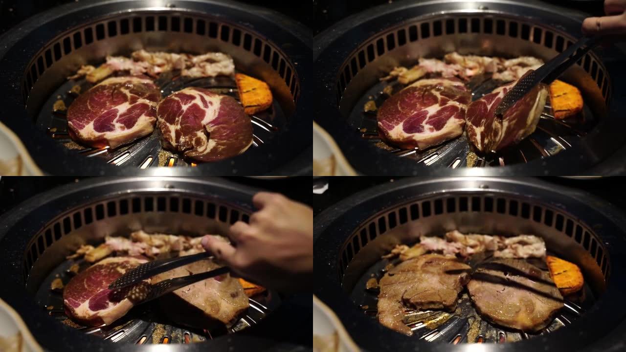 在传统的韩国餐厅，用手握钳在韩国烧烤盘上倒切猪肉。