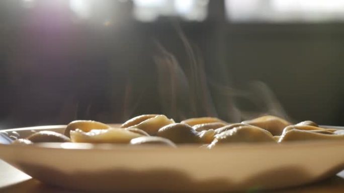 桌上放着一碗热腾腾的饺子。蒸汽从饺子中升起