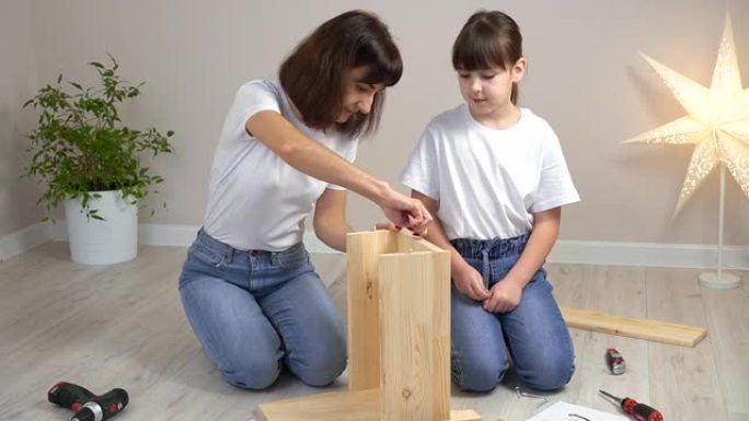 幸福的家庭母女俩一起组装木制家具。DIY概念