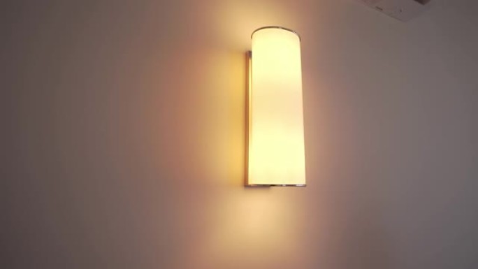 壁灯挂在酒店或公寓的白色墙上。有人关灯