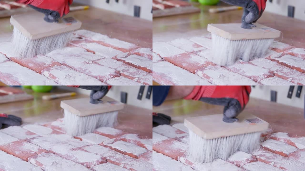 戴着橡胶手套的工匠用木刷扫除砖铸坯上的白色石膏残渣。外墙手工砖