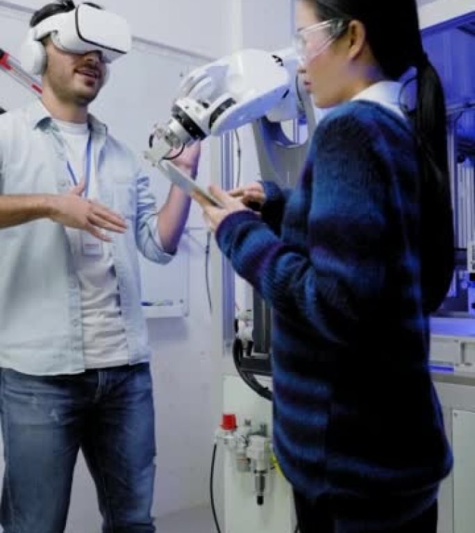 年轻的亚洲软件工程师通过使用虚拟现实模拟眼镜教机器人手臂具有像人类手势一样的运动系统，而另一位年轻的