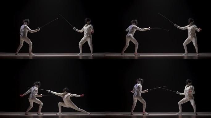 黑色背景上两名女性击剑手的决斗。合作伙伴展示了用剑杆击剑的技巧，练习了攻击元素。穿着白色制服和面具的