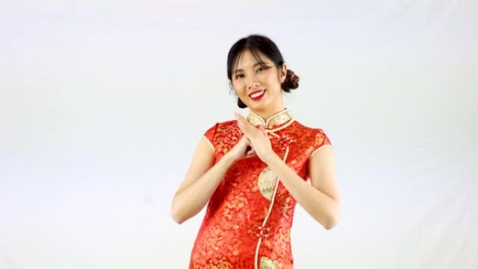 4k视频，亚洲女性穿着红色传统东方服装，白色背景上孤立的中国问候手势。中国新年概念风格。