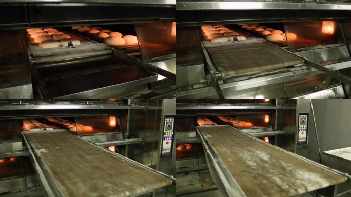 面包师手动拉动甲板烤箱装载机，将生面包面团移入烤箱-在面包店制作面包