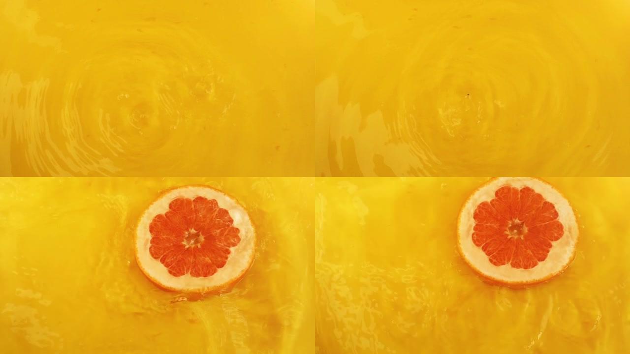 柚子片掉入橙色背景下的水中。慢动作。