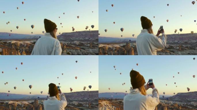 土耳其卡帕多西亚-2019年11月: 年轻女性用苹果手机给气球拍照
