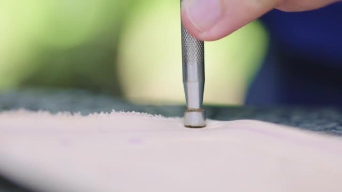 工匠使用工具在皮革上压花图案。