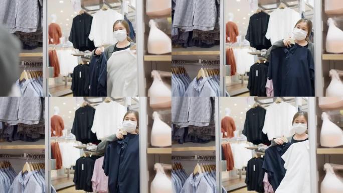 戴着口罩的亚洲女人在时装店试穿衣服，照镜子。