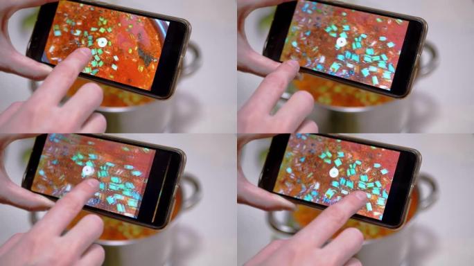 一名妇女在智能手机上看着传统的乌克兰红色罗宋汤的照片