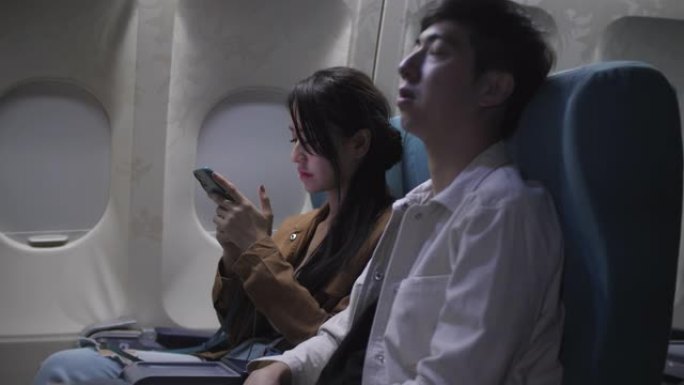 夜间飞行时在飞机上使用智能手机的女乘客