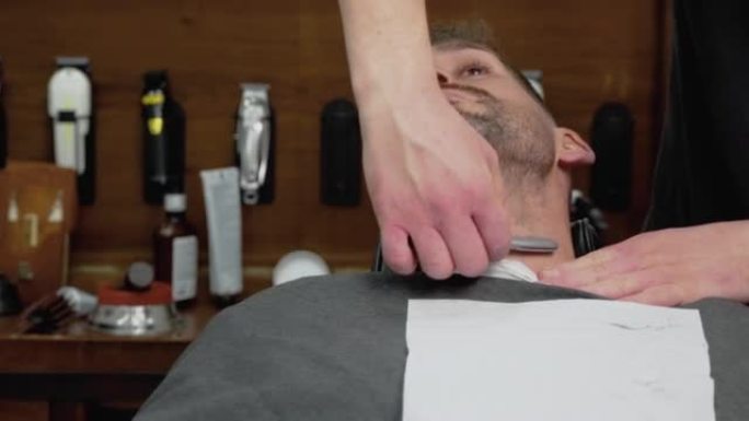 理发师用锋利的剃刀刮胡子的男性。高质量4k镜头
