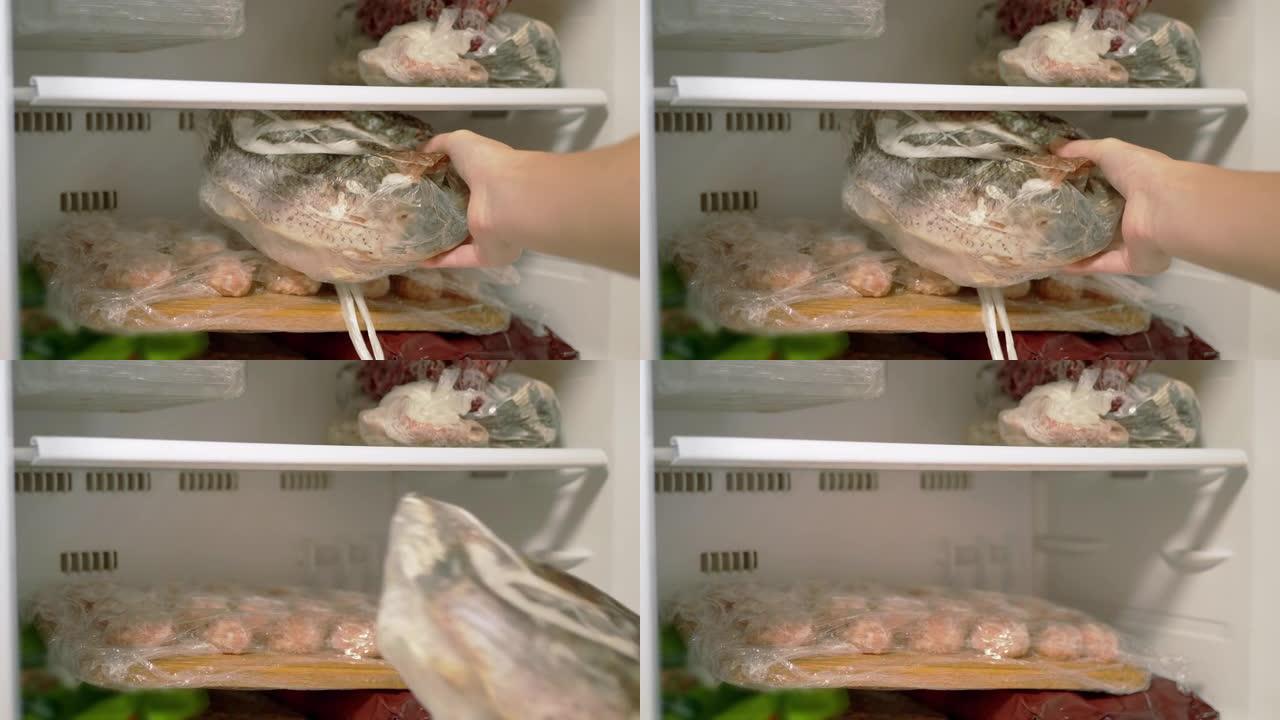雌性的手从冰柜里取出冷冻鱼。4K.特写。慢动作