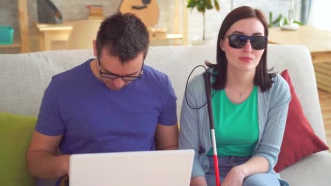 用笔记本电脑关闭年轻人帮助视力受损的女人