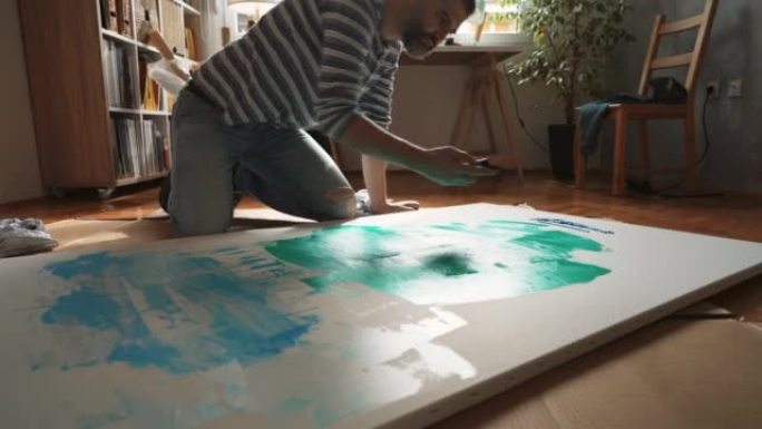 男艺术家从画布上的油漆管中挤压油漆